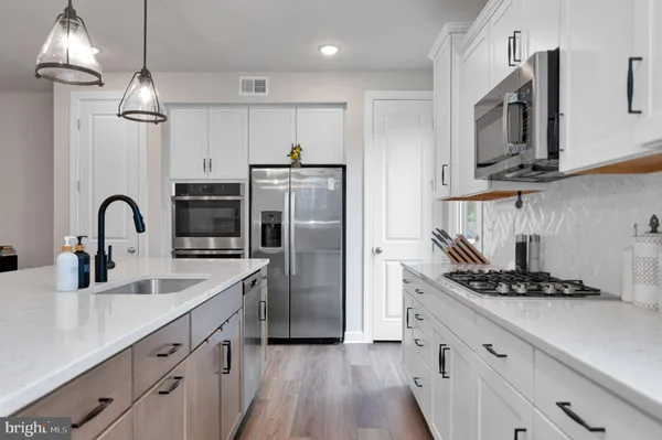 a kitchen with stainless steel appliances a sink cabinets and wooden floor