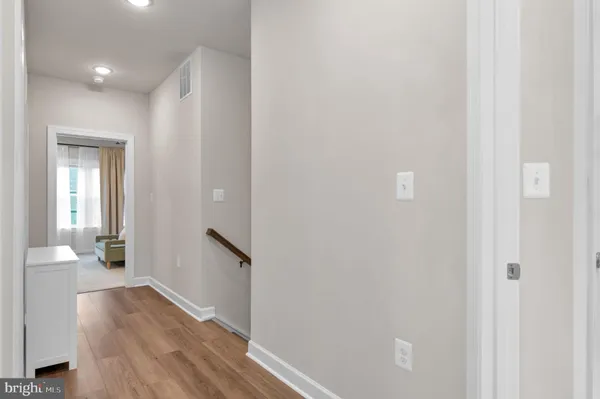 a view of a hallway with wooden floor and a bathroom