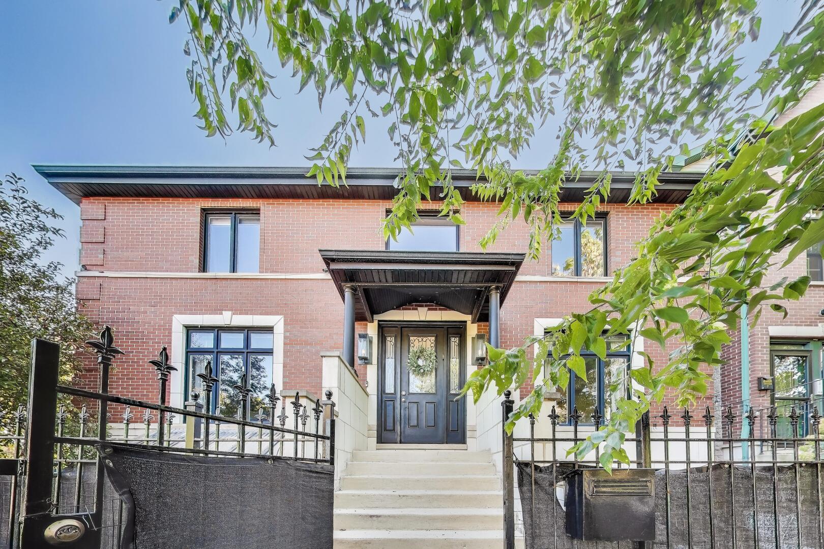 a front view of a house with glass windows and plants