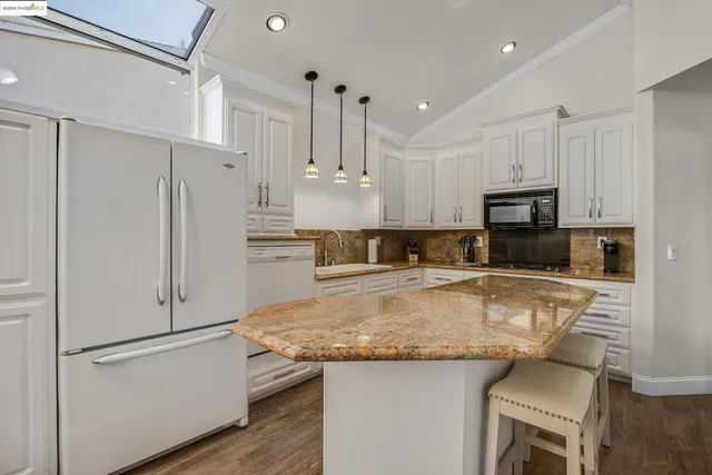 a kitchen with kitchen island a white counter top space cabinets and stainless steel appliances