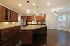 a kitchen with granite countertop kitchen island stainless steel appliances sink cabinets and wooden floor