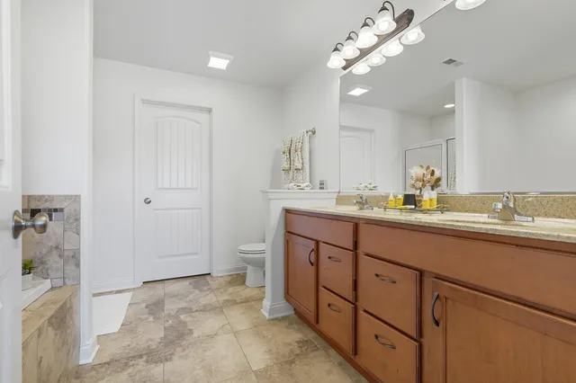 a spacious bathroom with a granite countertop sink a toilet and a mirror