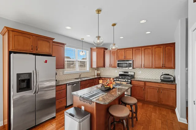 a kitchen with granite countertop a stove a sink dishwasher a refrigerator with a dining table and chairs