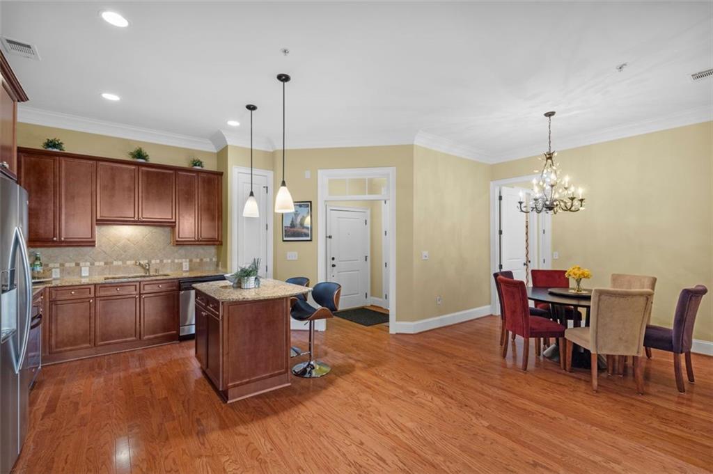 3635 East Paces Circle, Unit 1103 Atlanta, GA 30326 - Photo 12 of 37 a kitchen with stainless steel appliances granite countertop a stove top oven a refrigerator a dining table and chairs with wooden floor