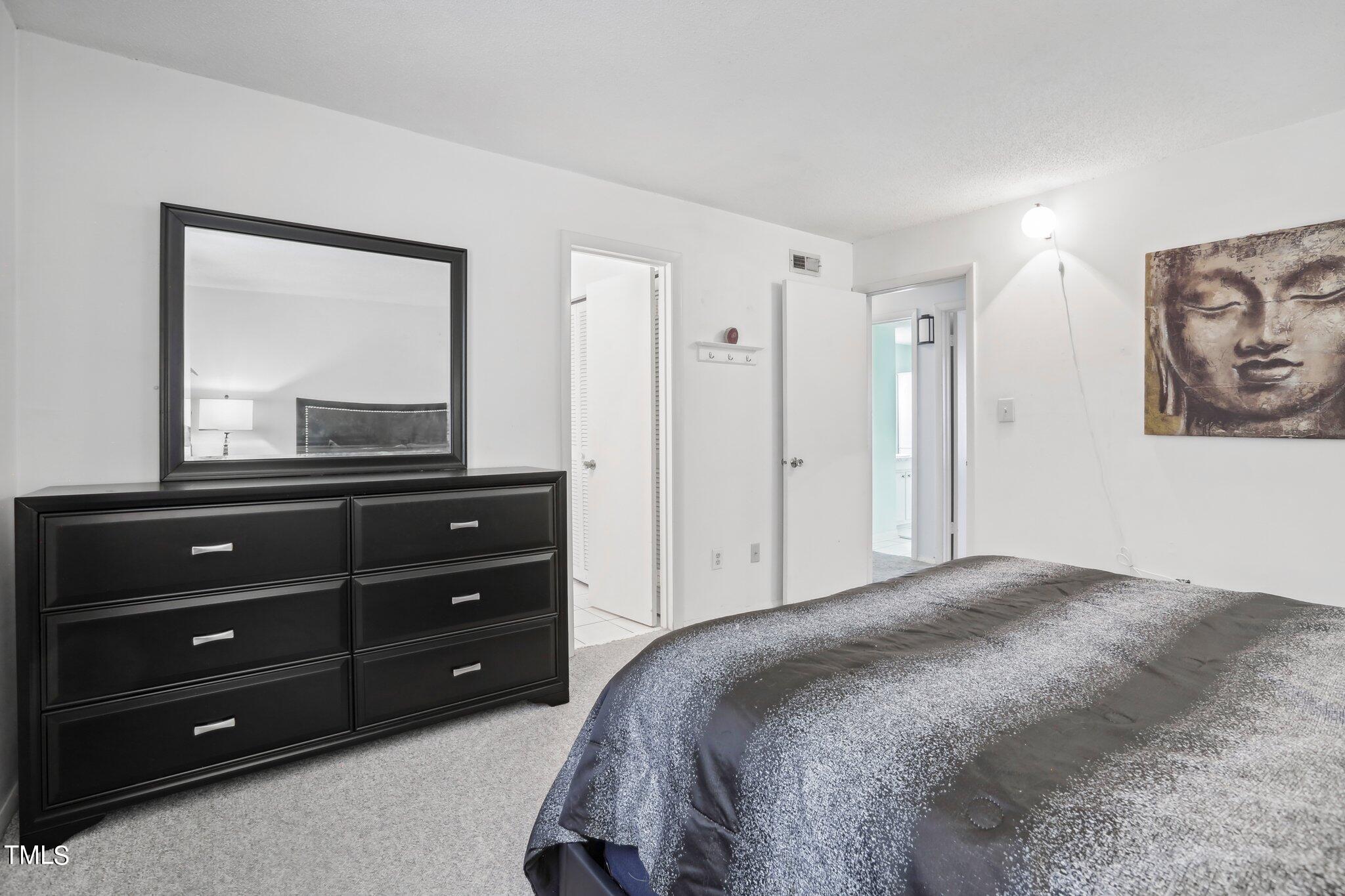 1216 Manassas Court, Unit E Raleigh, NC 27609 - Photo 15 of 20 a bedroom with a bed and a mirror on dresser