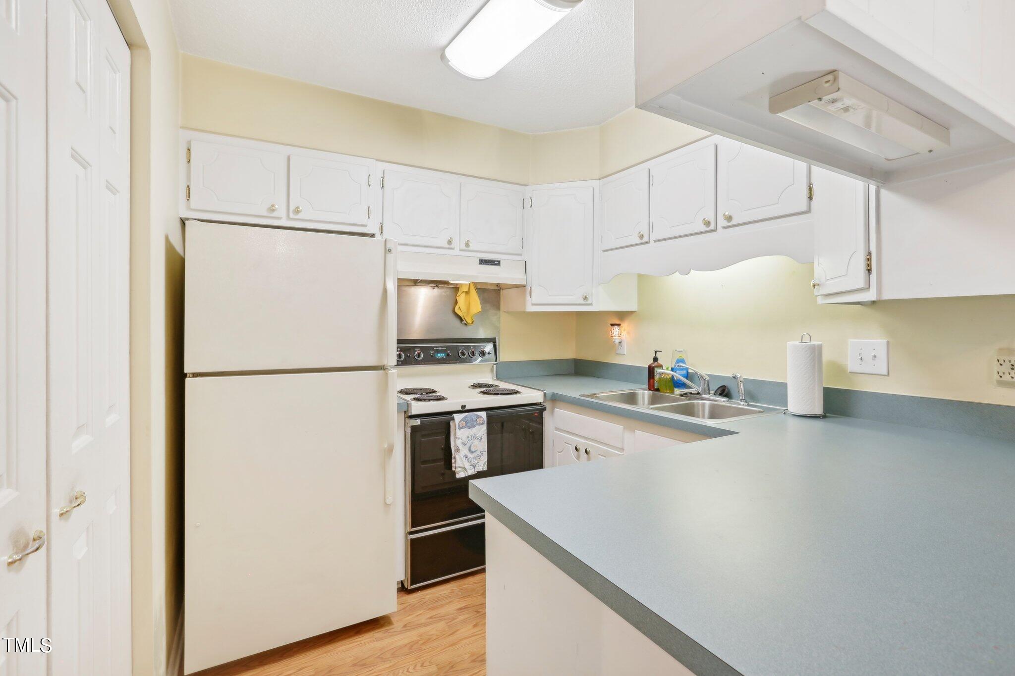 1216 Manassas Court, Unit E Raleigh, NC 27609 - Photo 10 of 20 a kitchen with a refrigerator a stove a sink and white cabinets