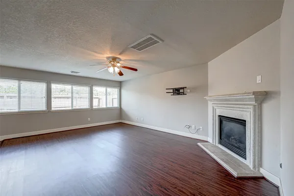 an empty room with wooden floor fireplace and windows
