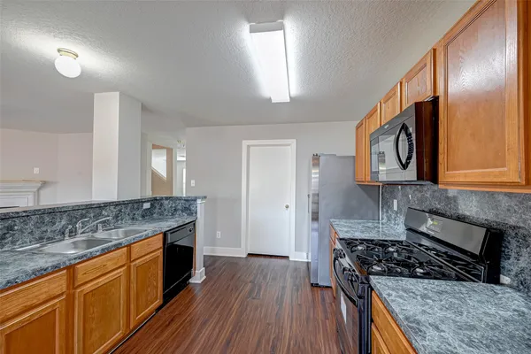 a kitchen with granite countertop a sink cabinets and stainless steel appliances