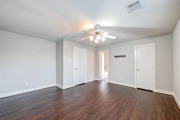 a view of an empty room with a chandelier fan and wooden floor