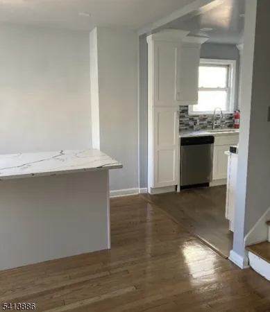 a view of an empty room with a kitchen and a window
