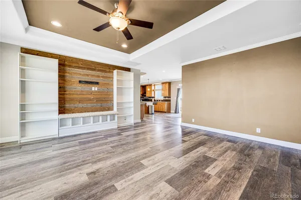 an empty room with wooden floor chandelier fan and windows