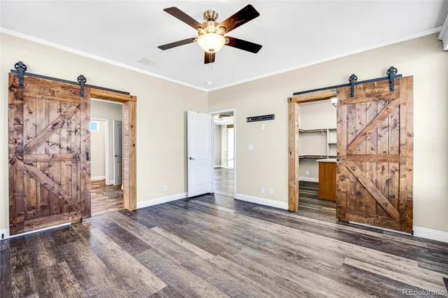 a view of empty room with wooden floor and fan