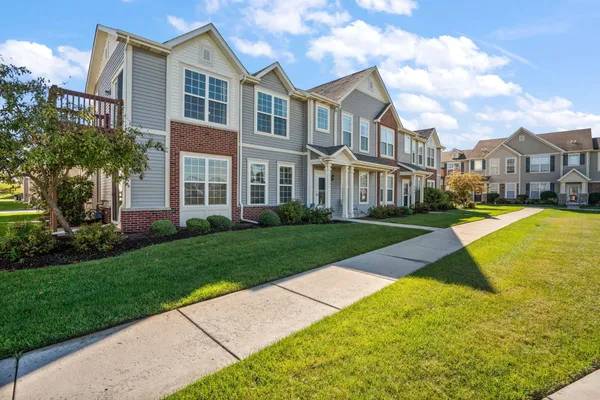 a view of a white house with a big yard and potted plants