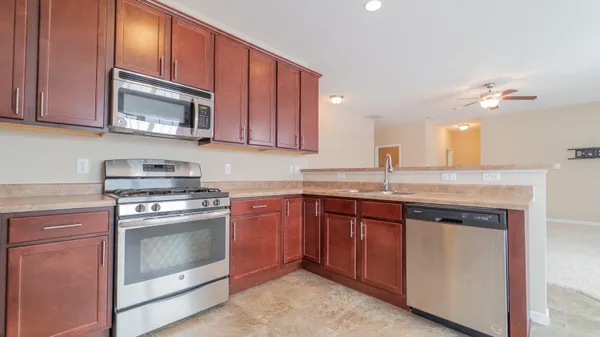 a kitchen with granite countertop wood cabinets stainless steel appliances and a sink