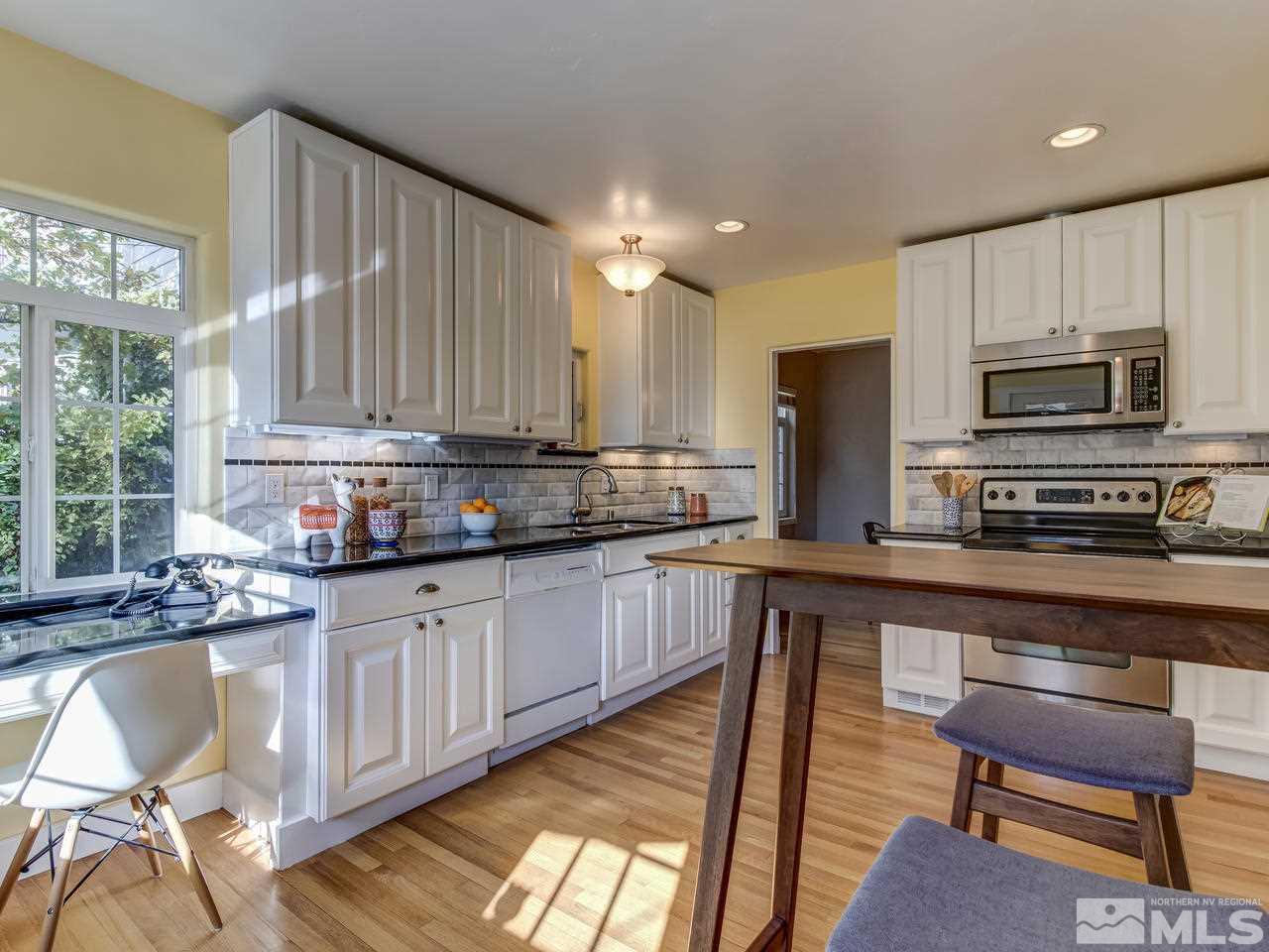 950 Walker Avenue Reno, NV 89509 - Photo 10 of 25 a kitchen with kitchen island granite countertop wooden cabinets a stove a microwave a island with a dining table and chairs