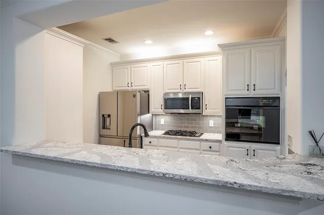 a kitchen with stainless steel appliances a sink a stove a microwave a sink and a counter top space