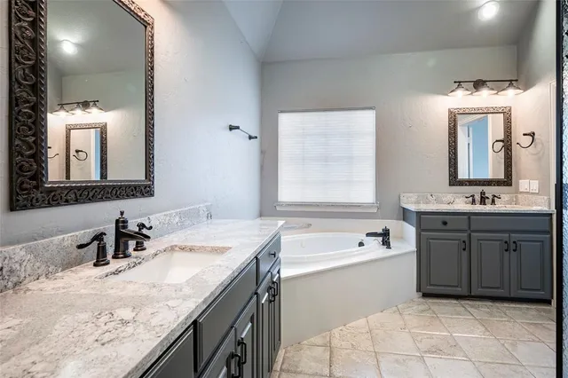 a bathroom with a granite countertop bathtub sink double and mirror