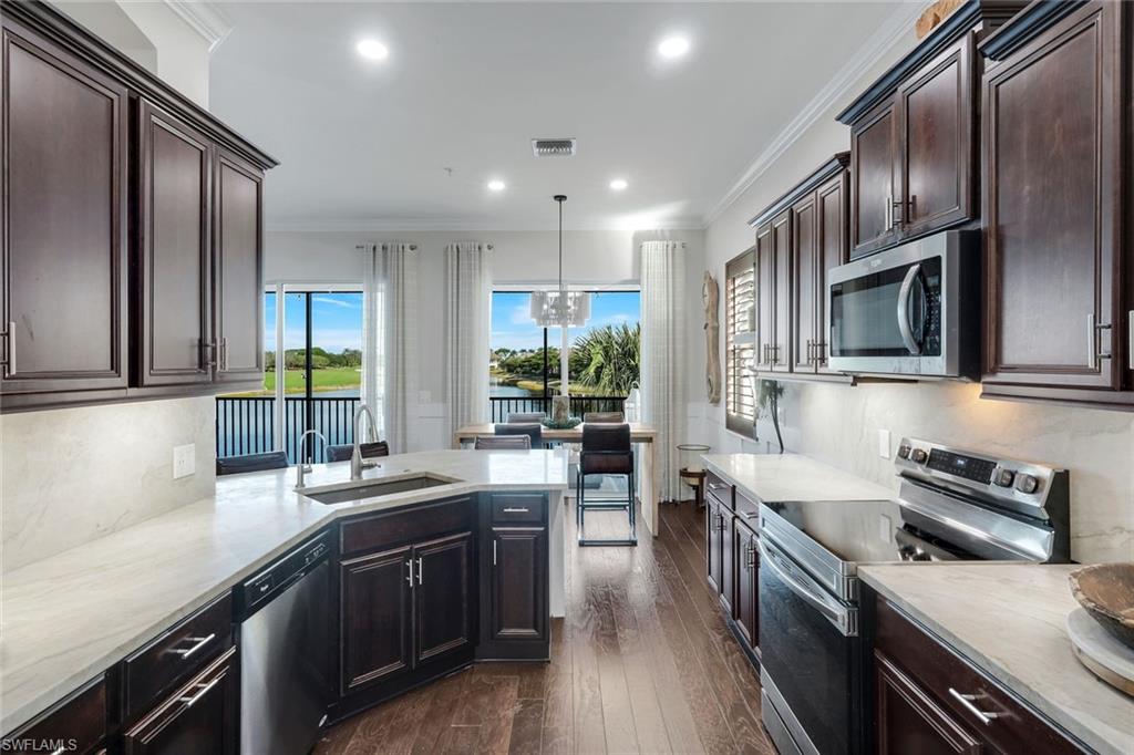8783 Coastline Court, Unit 202 Naples, FL 34120 - Photo 15 of 49 a kitchen with stainless steel appliances granite countertop a sink stove microwave and refrigerator