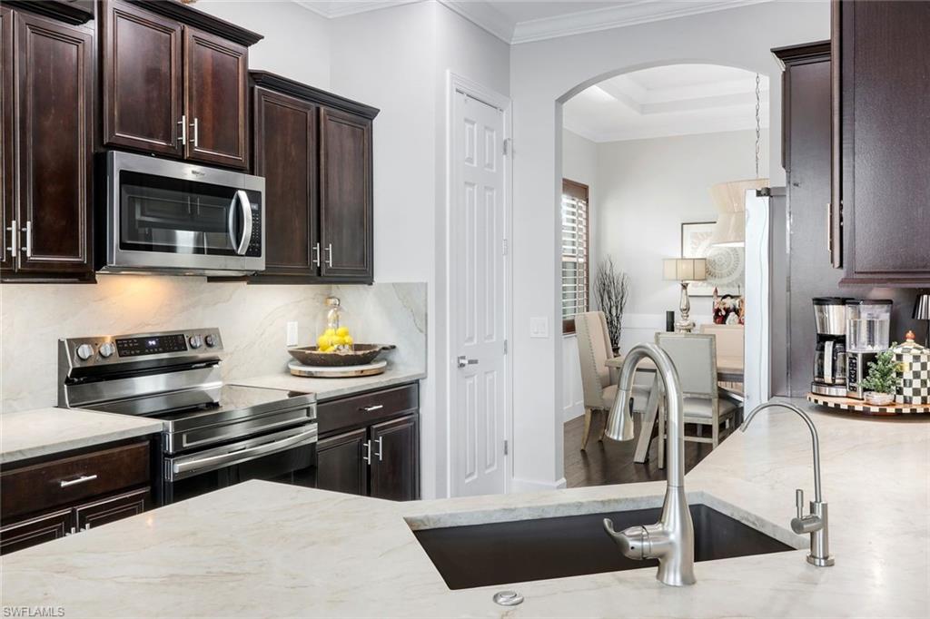 8783 Coastline Court, Unit 202 Naples, FL 34120 - Photo 18 of 49 a kitchen with stainless steel appliances kitchen island granite countertop a stove and cabinets