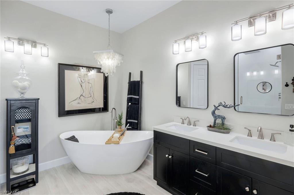 8783 Coastline Court, Unit 202 Naples, FL 34120 - Photo 24 of 49 a bathroom with a double vanity sink tub and mirror