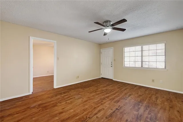 a view of an empty room with window and wooden floor