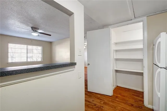 a view of empty room with wooden floor and fan