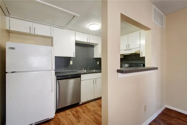 a kitchen with stainless steel appliances a refrigerator a sink and white cabinets
