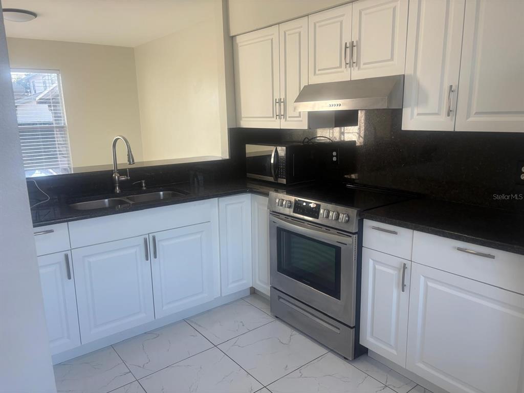 3216 Hempstead Avenue Kissimmee, FL 34741 - Photo 4 of 13 a kitchen with granite countertop white cabinets and appliances