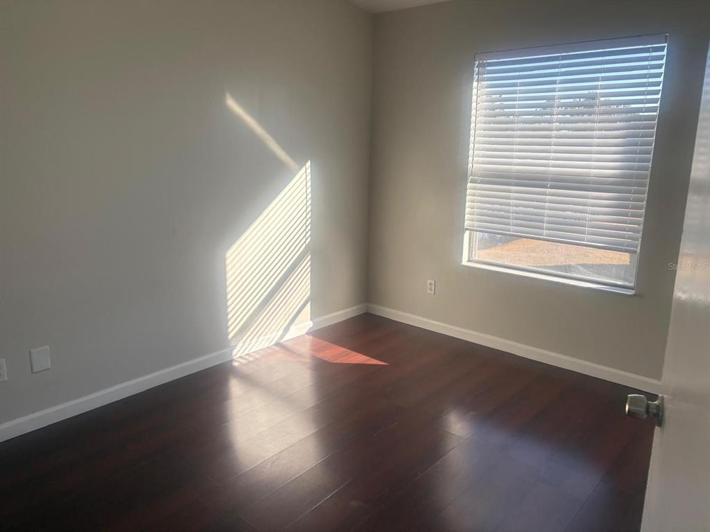 3216 Hempstead Avenue Kissimmee, FL 34741 - Photo 9 of 13 a view of an empty room with wooden floor and a window