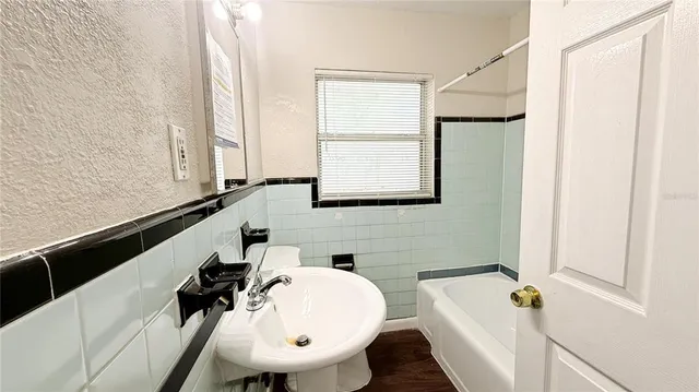a bathroom with a sink and mirror with bathtub