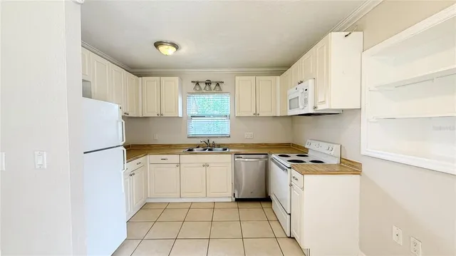 a kitchen with a white cabinets a sink a stove a refrigerator and white cabinets