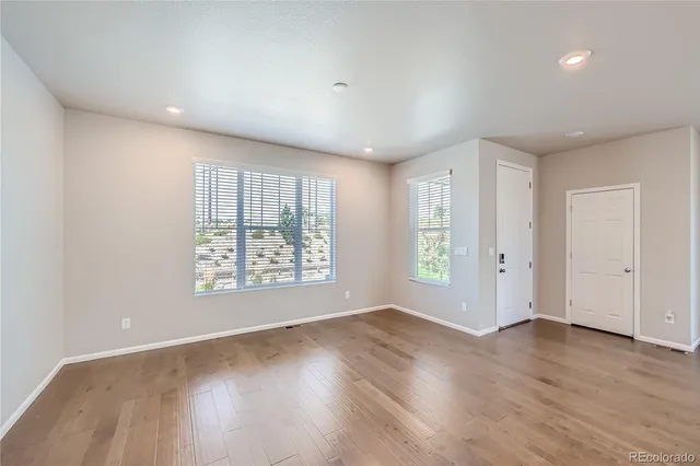 an empty room with wooden floor and windows