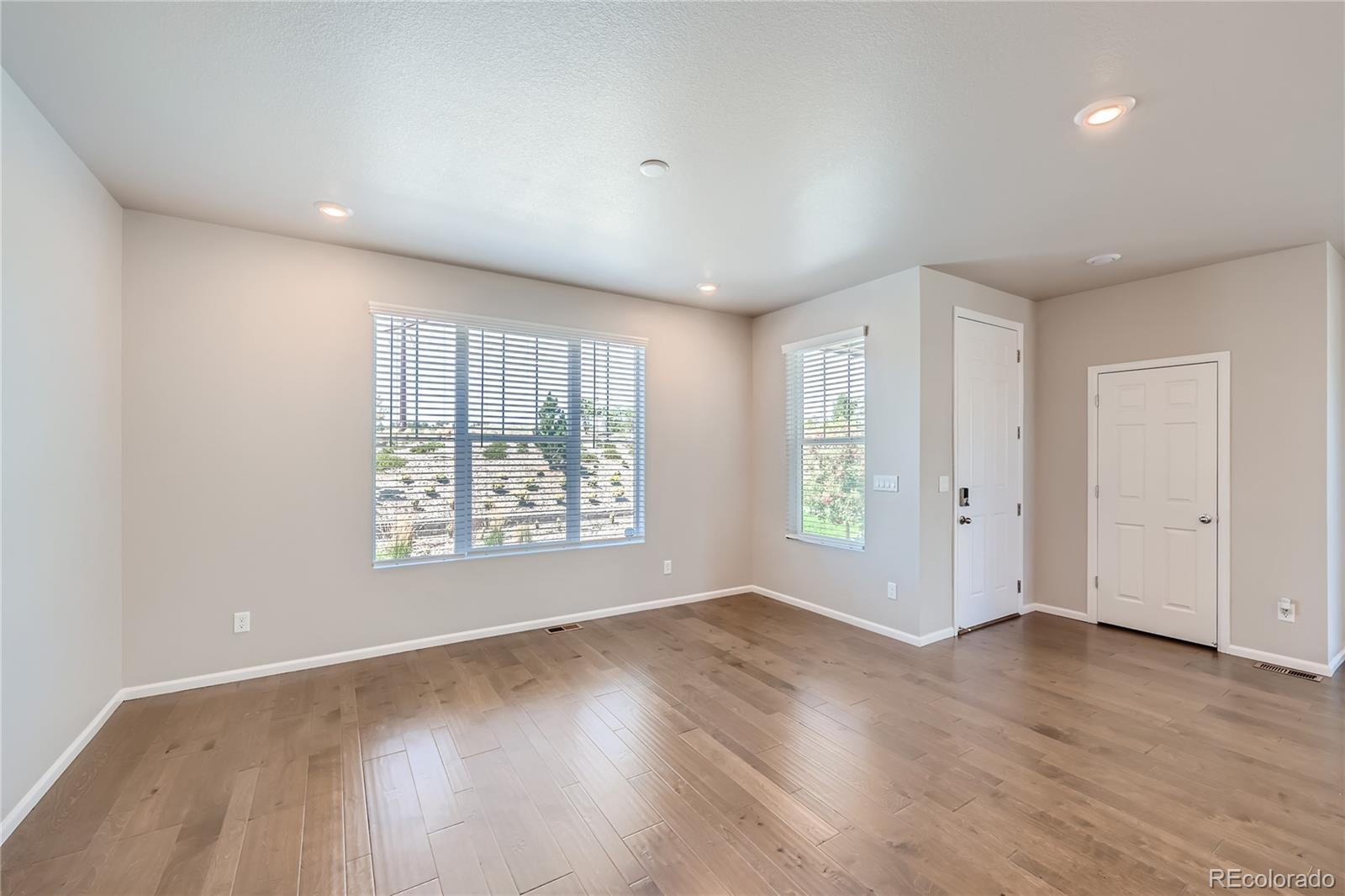 7199 Othello Street Castle Pines, CO 80108 - Photo 11 of 28 a view of an empty room with wooden floor and a window