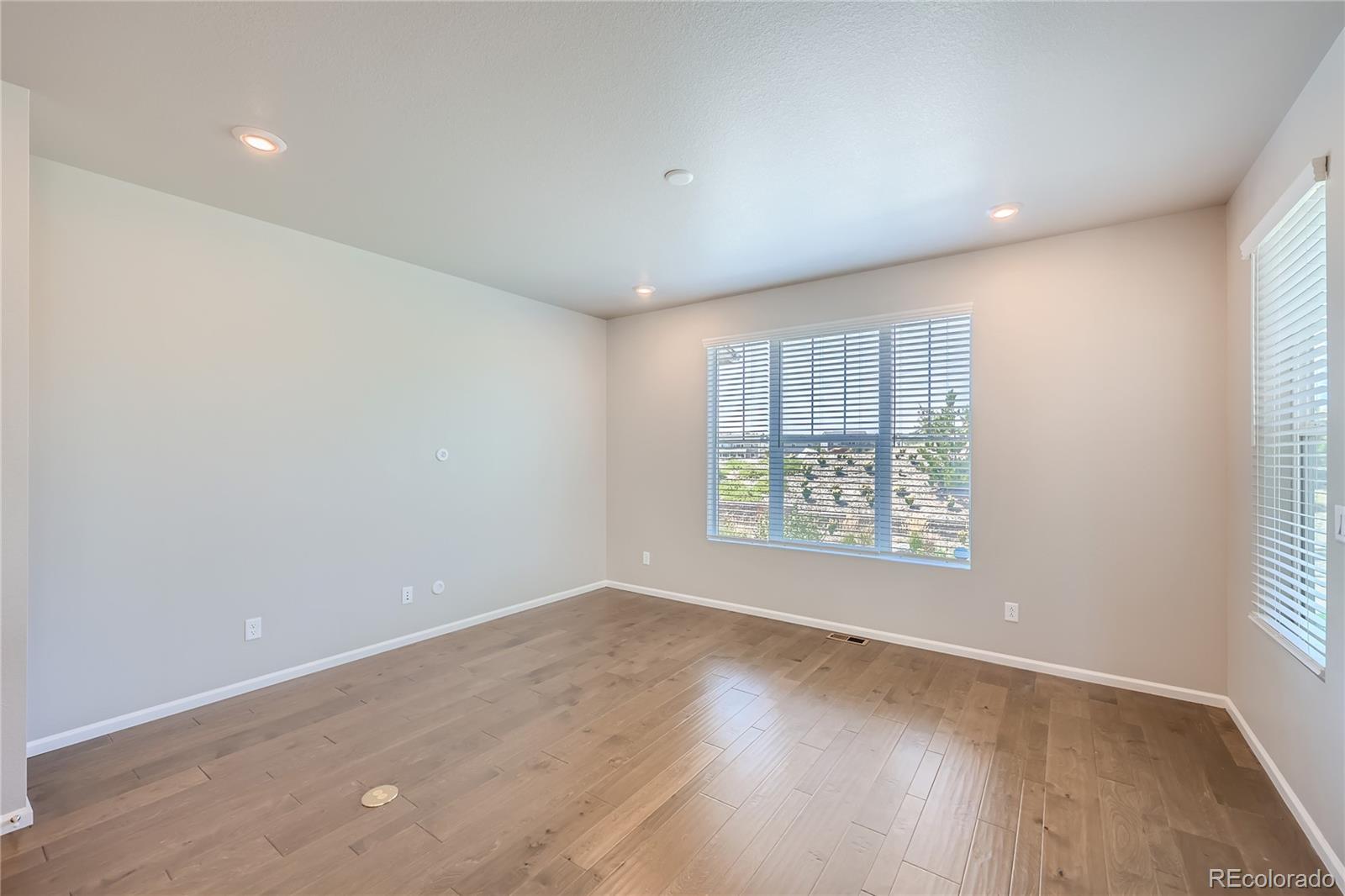 7199 Othello Street Castle Pines, CO 80108 - Photo 12 of 28 an empty room with wooden floor and windows