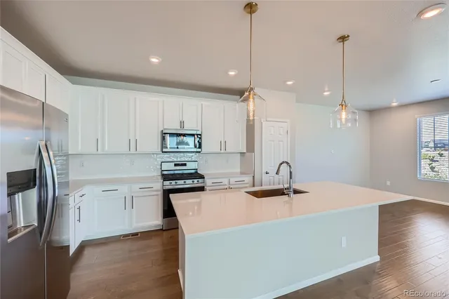 a kitchen with stainless steel appliances granite countertop a sink a stove a refrigerator and island with wooden floor