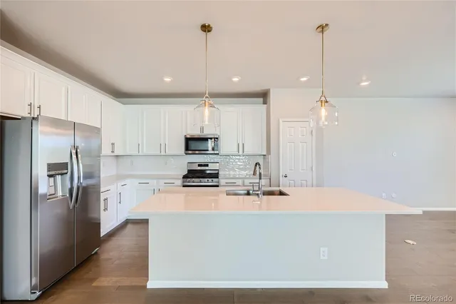 a kitchen with stainless steel appliances a refrigerator a stove a sink and a chairs