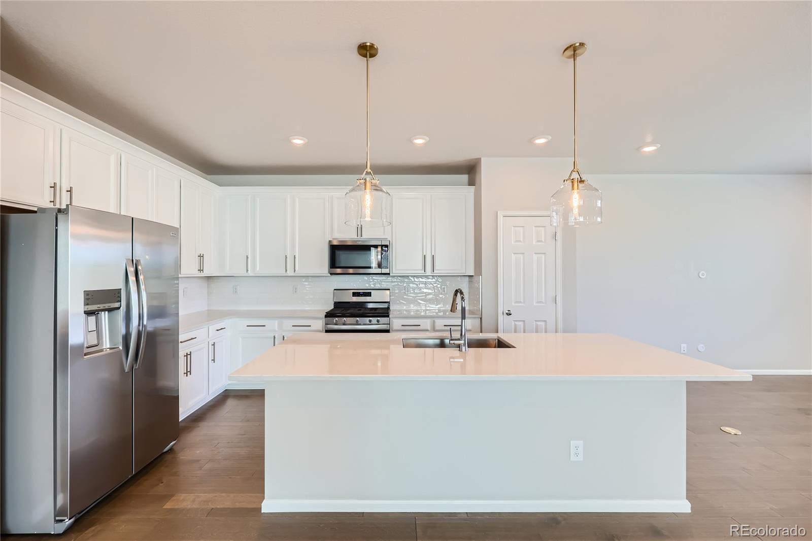 7199 Othello Street Castle Pines, CO 80108 - Photo 5 of 28 a kitchen with stainless steel appliances a refrigerator a stove a sink and a chairs