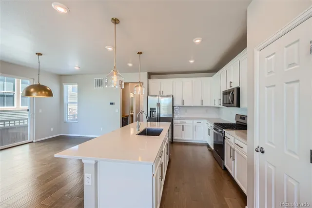 a kitchen with stainless steel appliances kitchen island granite countertop a refrigerator a stove top oven a sink and dishwasher with wooden floor