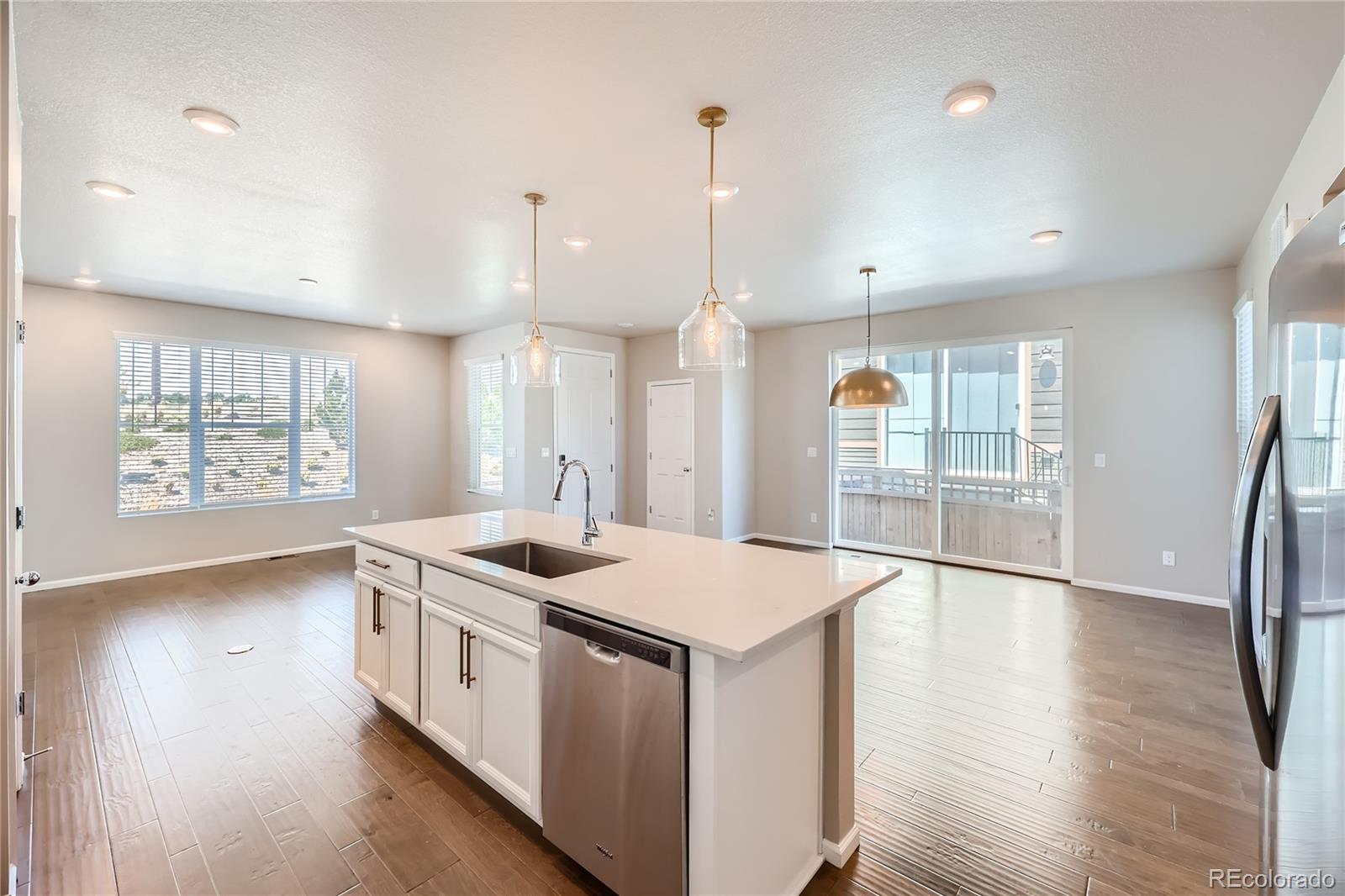 7199 Othello Street Castle Pines, CO 80108 - Photo 8 of 28 a kitchen that has a sink a stove and wooden floor