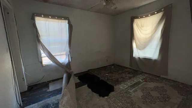 a view of a hallway to a livingroom with wooden floor and a window