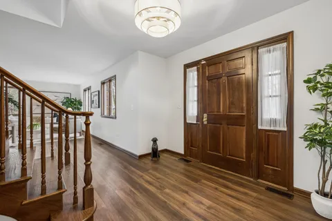 a living room with wooden floor stairs and a potted plant