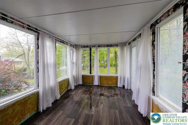 a view of empty room with wooden floor and floor to ceiling window