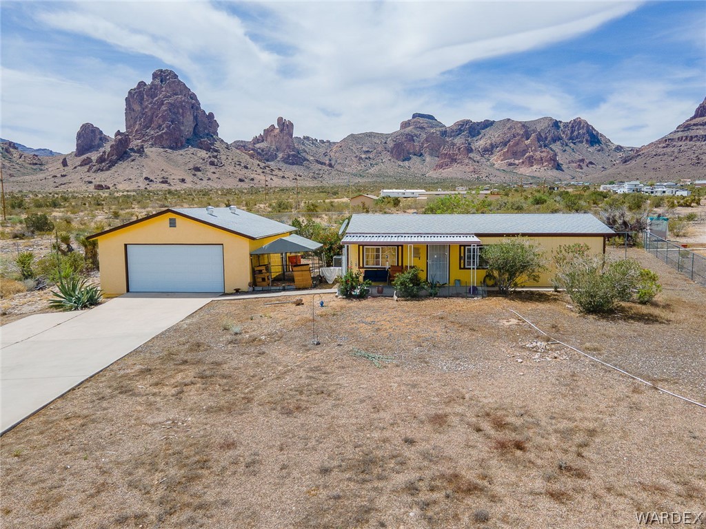 2465 Egar Road Golden Valley, AZ 86413 - Photo 67 of 98 The property features a yellow exterior, a main residence with a covered porch, and a detached garage with a driveway