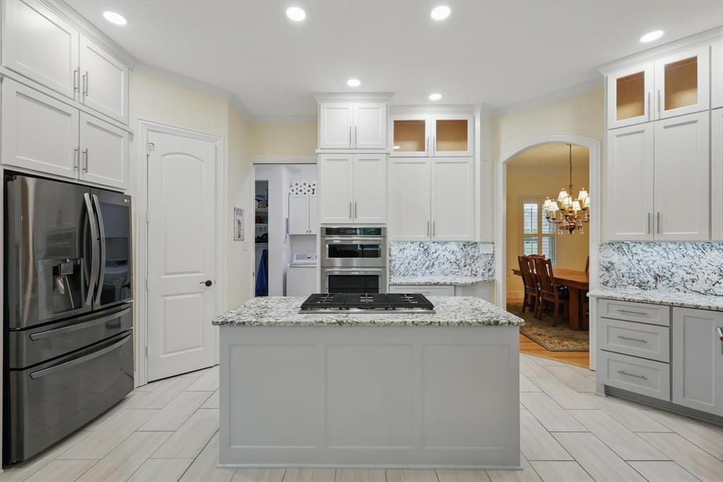 8517 Stallion Street Denton, TX 76208 - Photo 9 of 36 a kitchen with kitchen island granite countertop cabinets and refrigerator