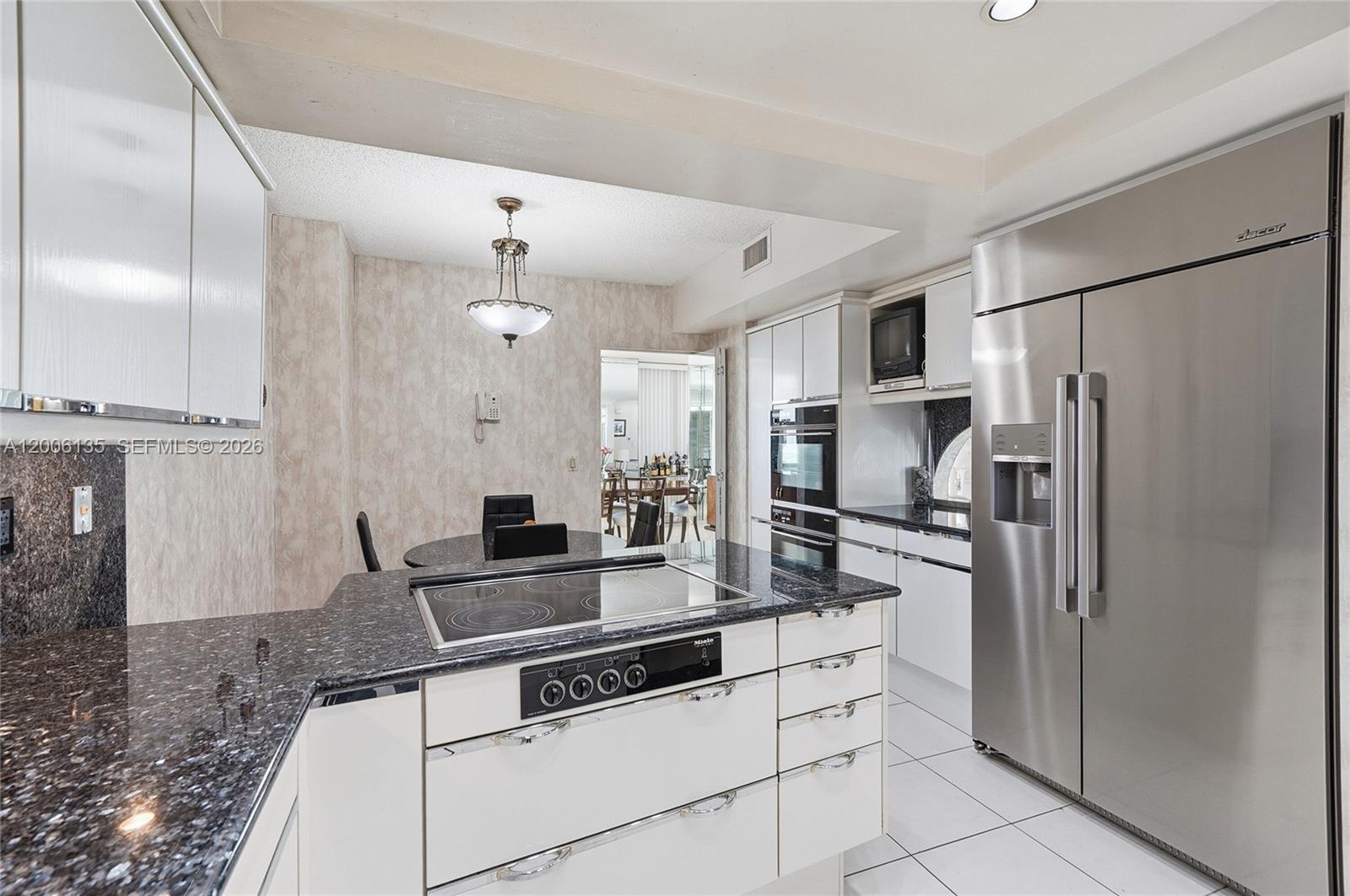 9801 Collins Avenue, Unit 14D Bal Harbour, FL 33154 - Photo 18 of 52 a kitchen with granite countertop a refrigerator and a stove top oven