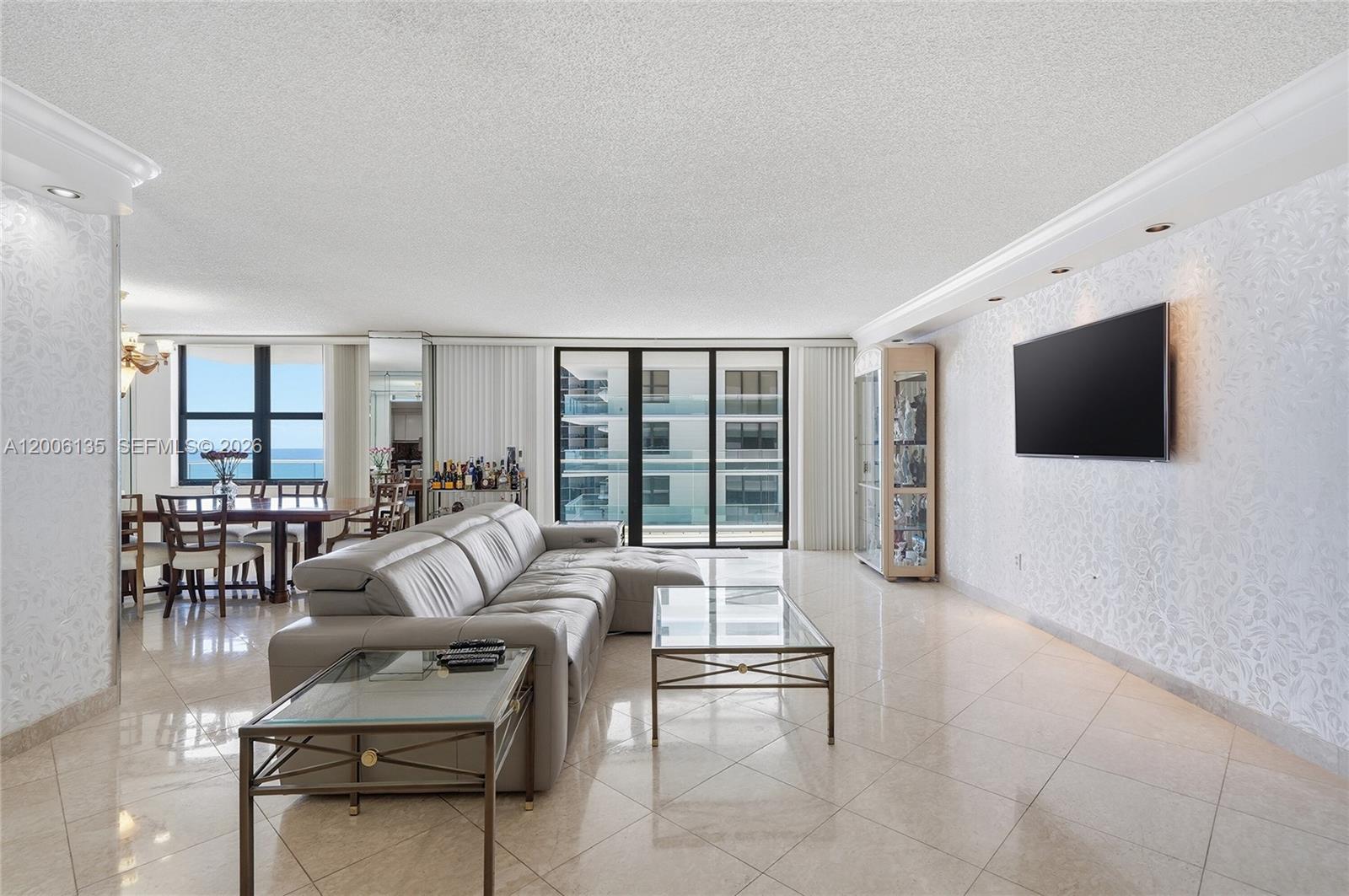 9801 Collins Avenue, Unit 14D Bal Harbour, FL 33154 - Photo 23 of 52 a living room with furniture a flat screen tv and a floor to ceiling window