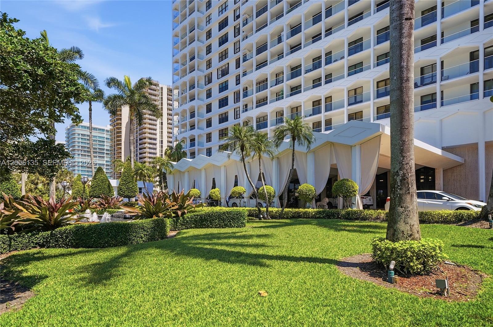 9801 Collins Avenue, Unit 14D Bal Harbour, FL 33154 - Photo 3 of 52 a front view of a building with a garden and trees