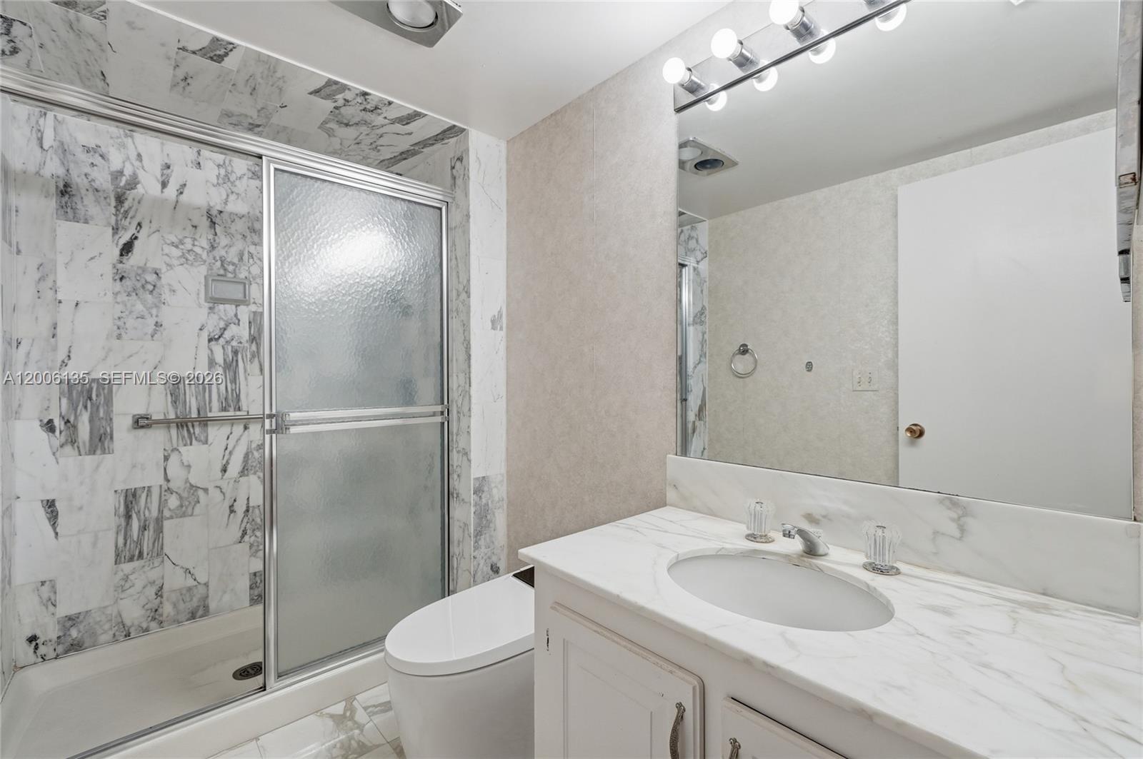 9801 Collins Avenue, Unit 14D Bal Harbour, FL 33154 - Photo 36 of 52 a bathroom with a granite countertop sink toilet and shower