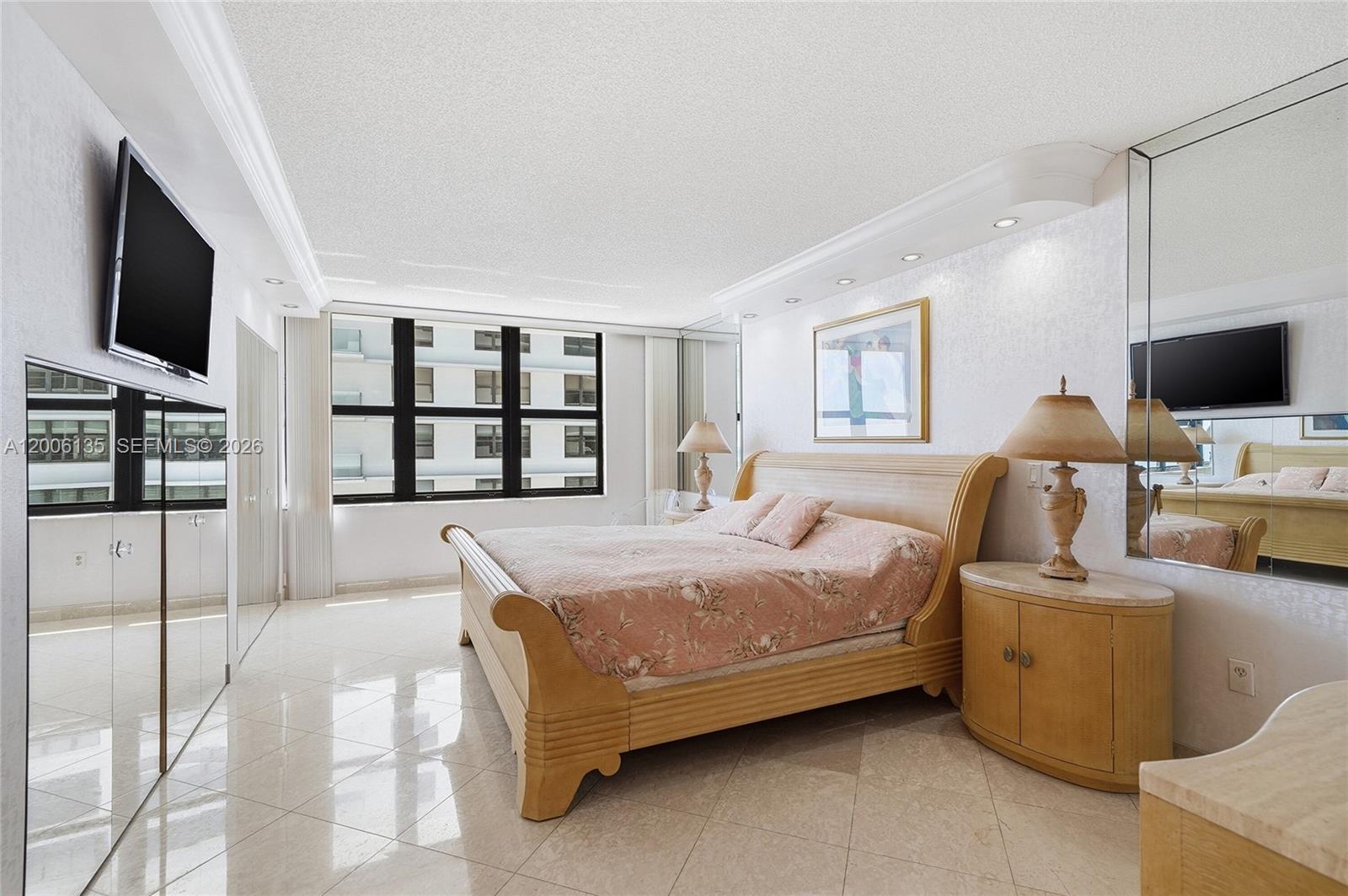 9801 Collins Avenue, Unit 14D Bal Harbour, FL 33154 - Photo 37 of 52 a bedroom with a bed wooden floor and flat screen tv