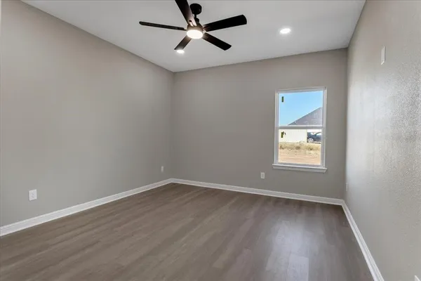 an empty room with wooden floor ceiling fan and windows